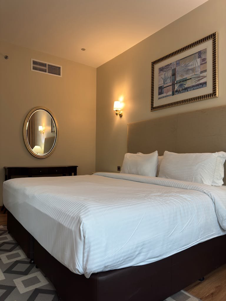 Spacious hotel room featuring a king-sized bed, modern decor, and warm lighting.