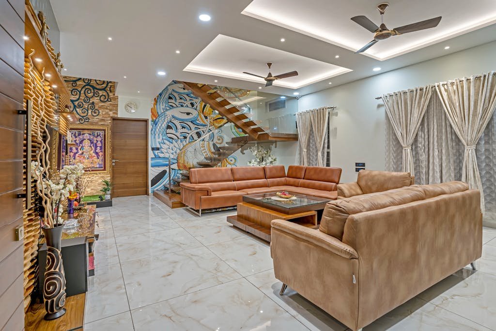 Stylish modern living room in Mumbai featuring leather sofas, artistic wall design, and wooden elements.